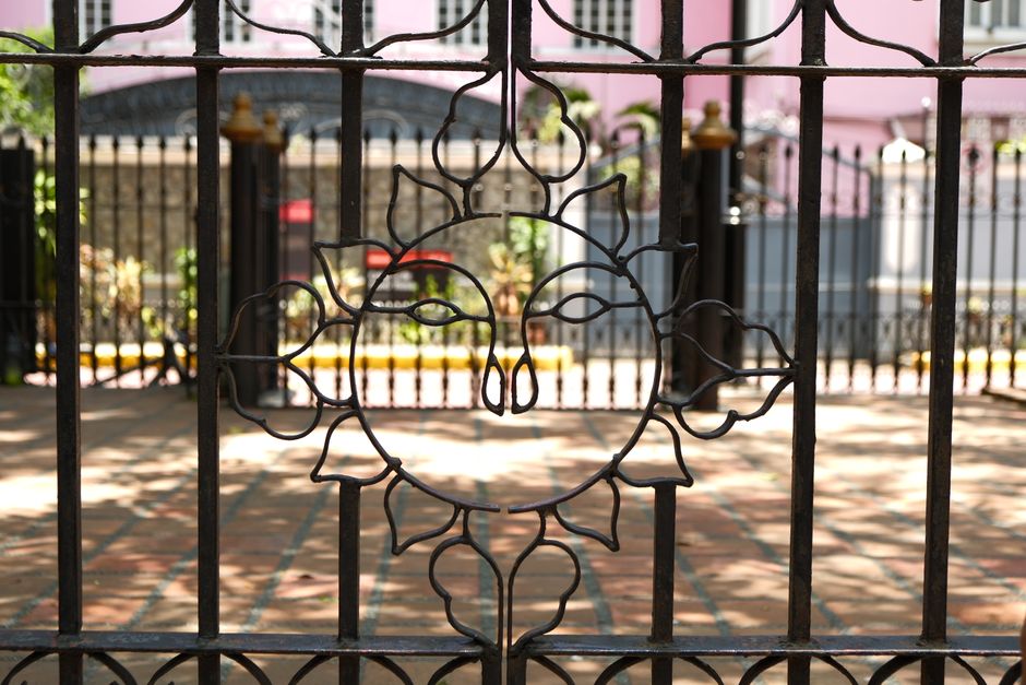 An iron gate featuring a sun design, set in a tranquil courtyard on a sunny day.