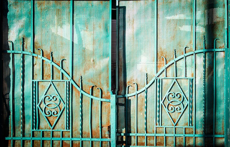 A turquoise metal gate with decorative patterns.